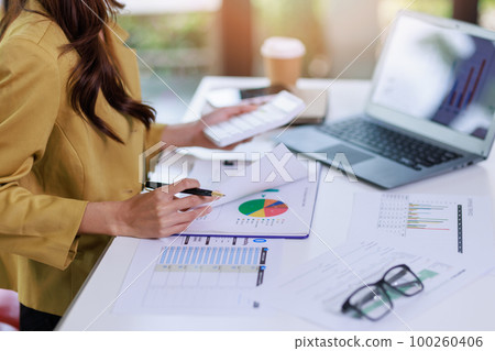 Concept of business invesment or woman working,Closeup businesswoman checking her invesment plan with analyzing document and business investment graph data by using calculator and computer laptop 100260406
