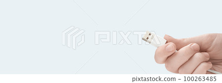 Hand holding white USB cable isolated on white background. Photo with copy space. 100263485