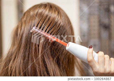 Woman uses darsonval for massage head's skin. 100264867