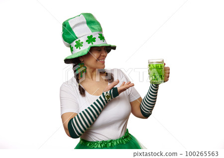 Multi-ethnic pretty woman in carnival costume for St Patrick's Day, smiling while posing with a mug of green beer on isolated white background. Irish culture and traditions. National holiday. March 17 Multi-ethnic pretty woman in carnival costume for St Patrick's Day, smiling while posing with a mug of green beer on isolated white background. Irish culture and traditions. National holiday. March 17 100265563