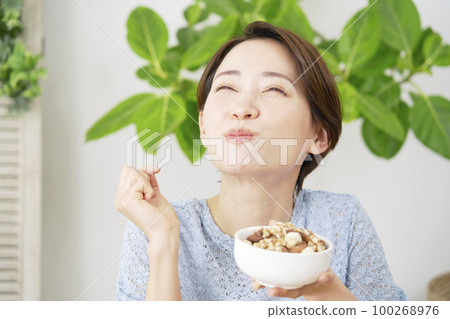 Woman eating nuts at home Woman eating nuts at home 100268976