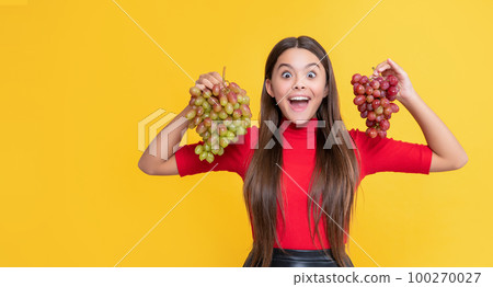 amazed girl hold bunch of grapes on yellow background amazed girl hold bunch of grapes on yellow background 100270027