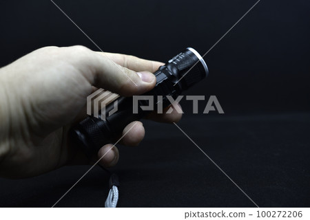 Metal black flashlight in hand. Pocket flashlight. 100272206