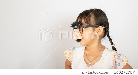 April Fool's Day. Portrait of Funny kid little girl clown wears a big nos and glasses and has a mustache isolated on white background with copy space, Happy smile child festive decor 100272797