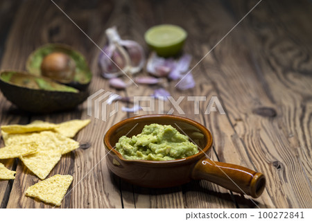 avocado dip flavored with garlic, chili, pepper, and lime juice with corn nachos 100272841
