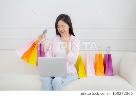 Young asian woman sitting on sofa using laptop computer shopping online. Young asian woman sitting on sofa using laptop computer shopping online. 100272866