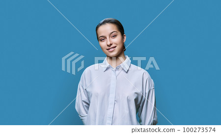 Portrait of smiling teenage girl in white shirt on blue background Portrait of smiling teenage girl in white shirt on blue background 100273574