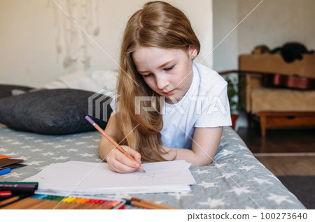 The girl after school plays at home, draws with pencils and felt-tip pens 100273640