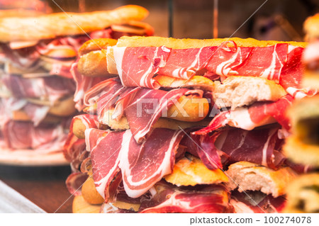 traditional Spanish bocadillos with Iberico jamon laid out in a slide on a shop window traditional Spanish bocadillos with Iberico jamon laid out in a slide on a shop window 100274078