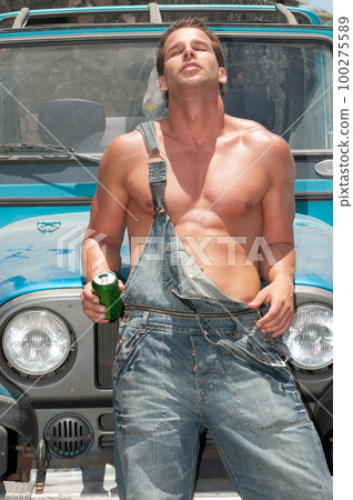 attractive athletic young man leaning on his car drinking beer attractive athletic young man leaning on his car drinking beer 100275589