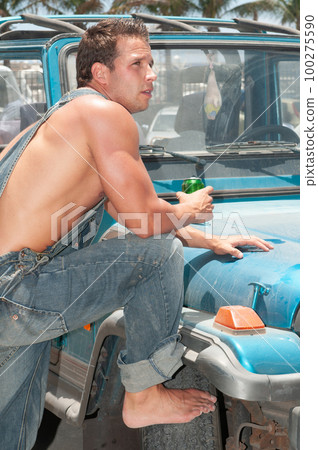 attractive athletic young man leaning on his car drinking beer attractive athletic young man leaning on his car drinking beer 100275590