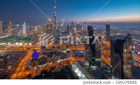 Aerial view of tallest towers in Dubai Downtown skyline and highway day to night timelapse. Aerial view of tallest towers in Dubai Downtown skyline and highway day to night timelapse. 100276888