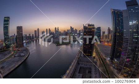 Cityscape panorama of skyscrapers in Dubai Business Bay with water canal aerial day to night timelapse 100276904