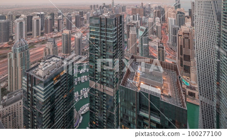 Dubai Marina and JLT district with traffic on highway between skyscrapers aerial night to day timelapse. Dubai Marina and JLT district with traffic on highway between skyscrapers aerial night to day timelapse. 100277100