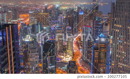 Skyline panoramic view of Dubai Marina showing canal surrounded by skyscrapers along shoreline day to night timelapse. DUBAI, UAE 100277105