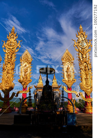 Serene Thai Monk Statue with Golden Sculptured Pillars Serene Thai Monk Statue with Golden Sculptured Pillars 100277192