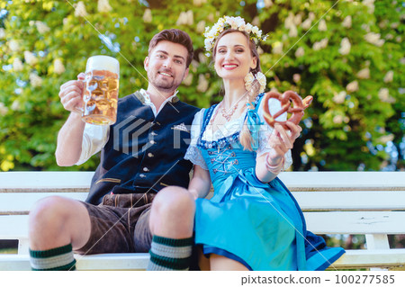 Couple in Bavaria sitting on bench toasting with beer Couple in Bavaria sitting on bench toasting with beer 100277585