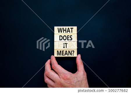 What does it mean symbol. Concept words What does it mean on wooden blocks. Businessman hand. Beautiful black table, black background, copy space. Business and what does it mean concept. 100277682