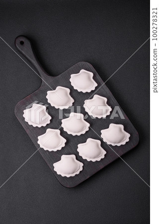 Raw frozen stuffed dumplings on a wooden cutting board Raw frozen stuffed dumplings on a wooden cutting board 100278321