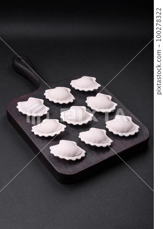 Raw frozen stuffed dumplings on a wooden cutting board Raw frozen stuffed dumplings on a wooden cutting board 100278322