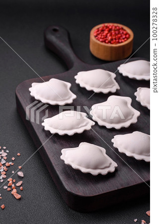 Raw frozen stuffed dumplings on a wooden cutting board Raw frozen stuffed dumplings on a wooden cutting board 100278328