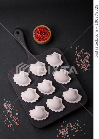 Raw frozen stuffed dumplings on a wooden cutting board Raw frozen stuffed dumplings on a wooden cutting board 100278329