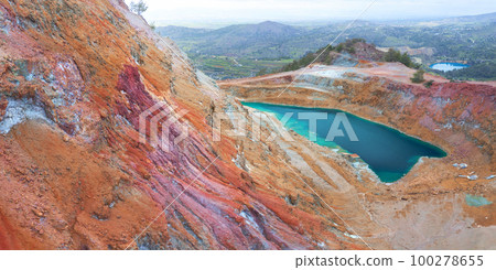 Abandoned copper mines of Cyprus. Colorful gossan (iron cap) of Alestos mine with open pit filled with water, and Memi mine lake at the distance 100278655