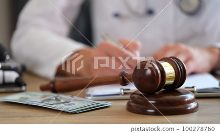 Judge gavel on hospital desk and doctor making notes in documents. 100278760