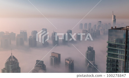 Fog covered JLT skyscrapers and marina towers near Sheikh Zayed Road aerial timelapse after sunrise. Residential buildings 100278847