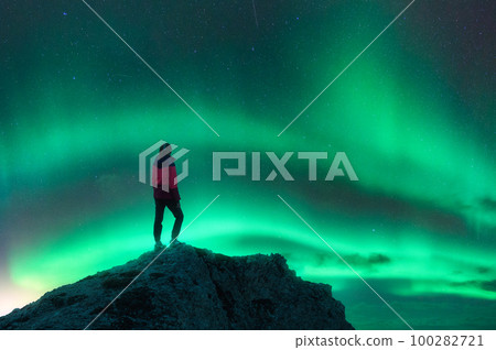 Northern lights and young woman on mountain peak at night. Auror Northern lights and young woman on mountain peak at night. Auror 100282721