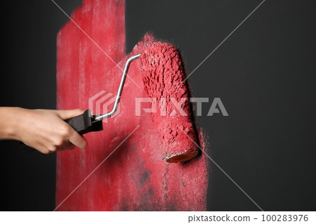 Woman painting grey wall with pink dye, closeup 100283976