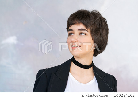 Portrait girl in black jacket with checker around her neck against wall. Pretty 100284102
