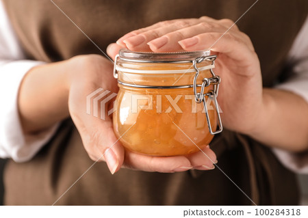 Woman with jar of delicious jam, closeup 100284318