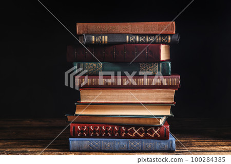 Collection of different books on wooden table against dark background 100284385