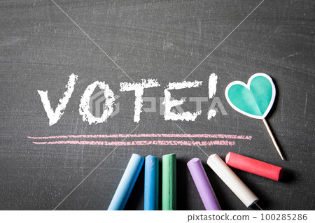 VOTE. text and colored pieces of chalk on a dark textured blackboard VOTE. text and colored pieces of chalk on a dark textured blackboard 100285286