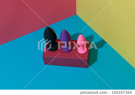 Different colored buttplug sex toys with contrast shadows. Anal toys for adult. Sex shop concept Different colored buttplug sex toys with contrast shadows. Anal toys for adult. Sex shop concept 100287369