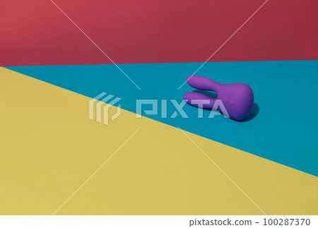 Violet dildo vibrator for clitoris on colored background with contrast shadows. Sex toy for adult 100287370