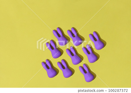 Many violet dildo vibrators for clitoris on yellow background. Sex toys for adult 100287372