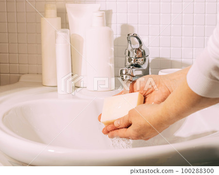 Woman washes her hands with soap over sink in bathroom. Hygiene and health cleanliness and body care Woman washes her hands with soap over sink in bathroom. Hygiene and health cleanliness and body care 100288300