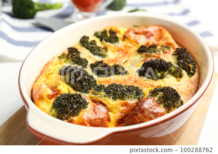Tasty broccoli casserole in baking dish on wooden board, closeup 100288762