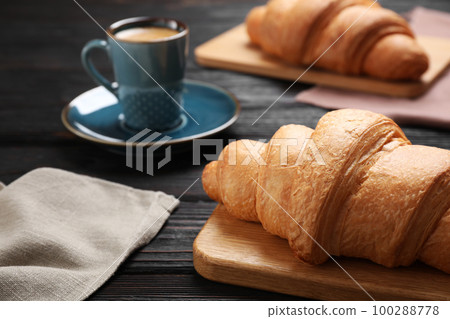 Tasty fresh croissants and coffee on black wooden table, closeup 100288778
