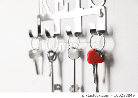 Metal key holder on light wall indoors, closeup Metal key holder on light wall indoors, closeup 100288849