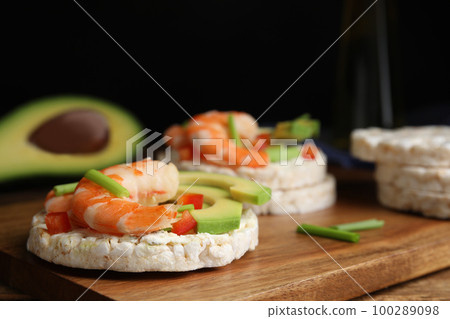 Puffed rice cakes with shrimps and avocado on wooden board, closeup Puffed rice cakes with shrimps and avocado on wooden board, closeup 100289098