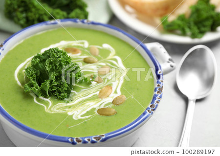 Tasty kale soup with pumpkin seeds on light grey table, closeup Tasty kale soup with pumpkin seeds on light grey table, closeup 100289197