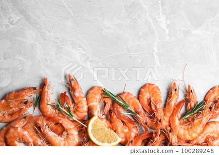 Delicious cooked shrimps with rosemary and lemon on grey marble table, flat lay. Space for text 100289248