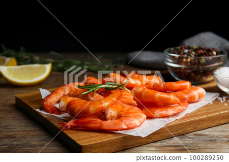 Delicious cooked shrimps with rosemary on wooden board Delicious cooked shrimps with rosemary on wooden board 100289250