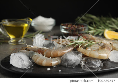 Raw shrimps with ice on grey table, closeup Raw shrimps with ice on grey table, closeup 100289257