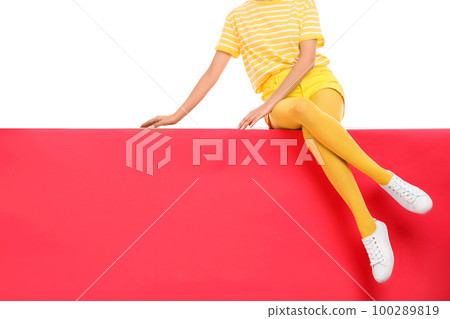 Woman wearing yellow tights sitting on color background, closeup. Space for text 100289819