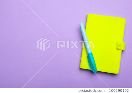 Green notebook and marker on lilac background, top view. Space for text 100290102