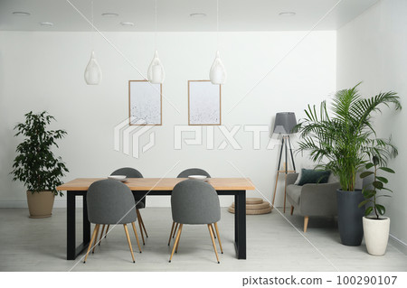 Stylish wooden table and chairs in light room. Modern interior design Stylish wooden table and chairs in light room. Modern interior design 100290107